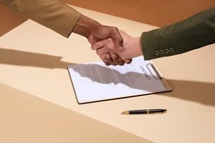Two people shaking hands over a signed document